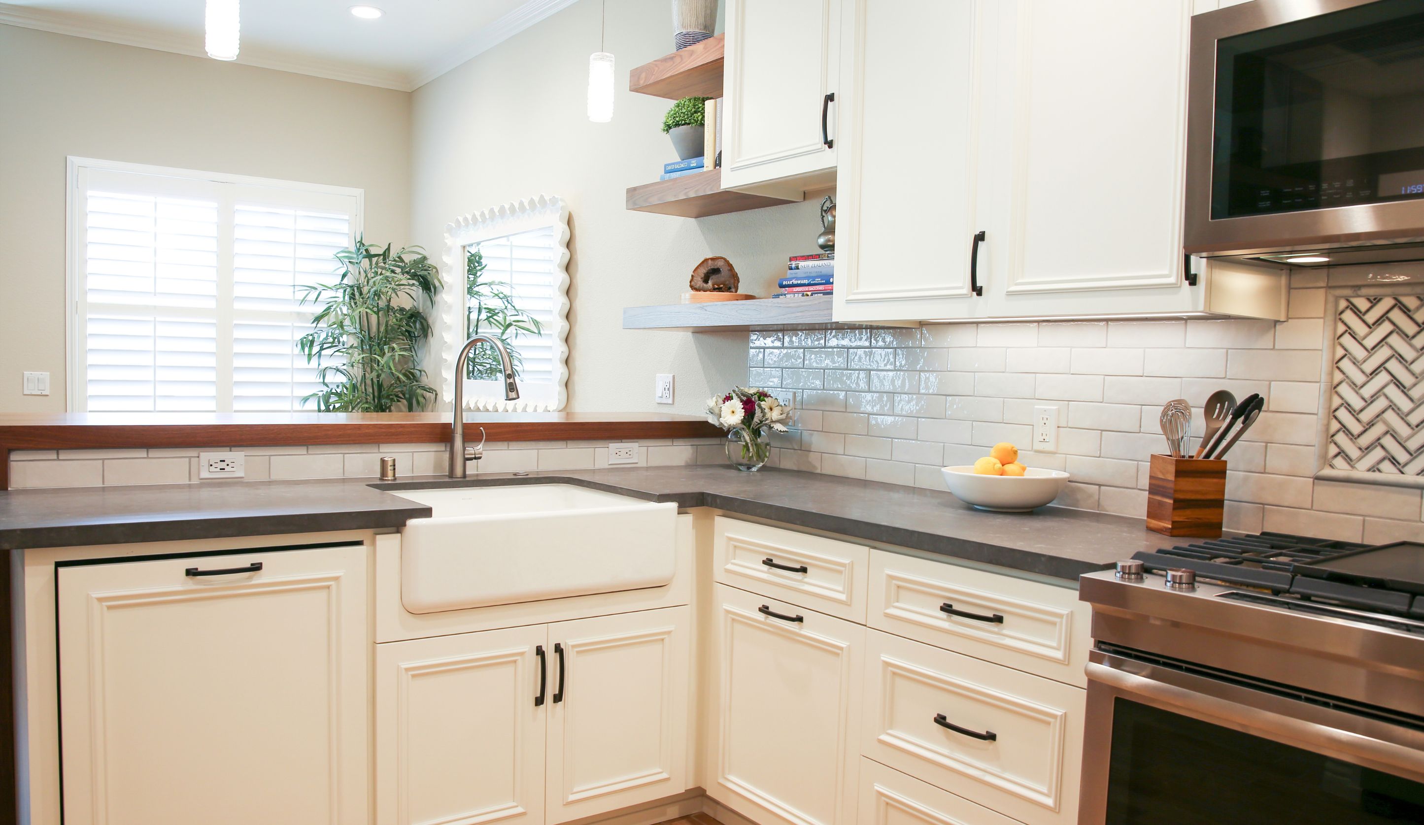 Carlsbad kitchen remodel with stainless gas range, microwave, white cabinetry and herringbone backsplash accent.