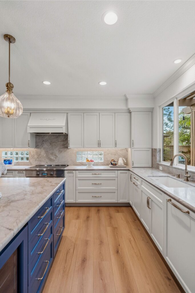 Carmel Valley kitchen remodel with white cabinetry, blue island, stone counters and wood-look flooring.