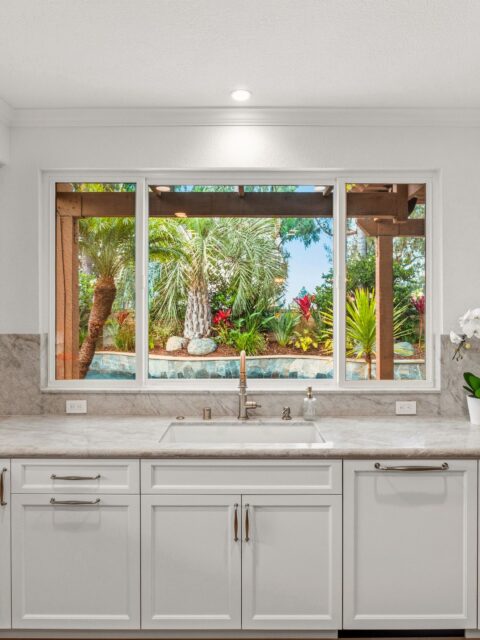 Carmel Valley kitchen remodel with white cabinetry, stone counters, apron sink and garden-facing window.