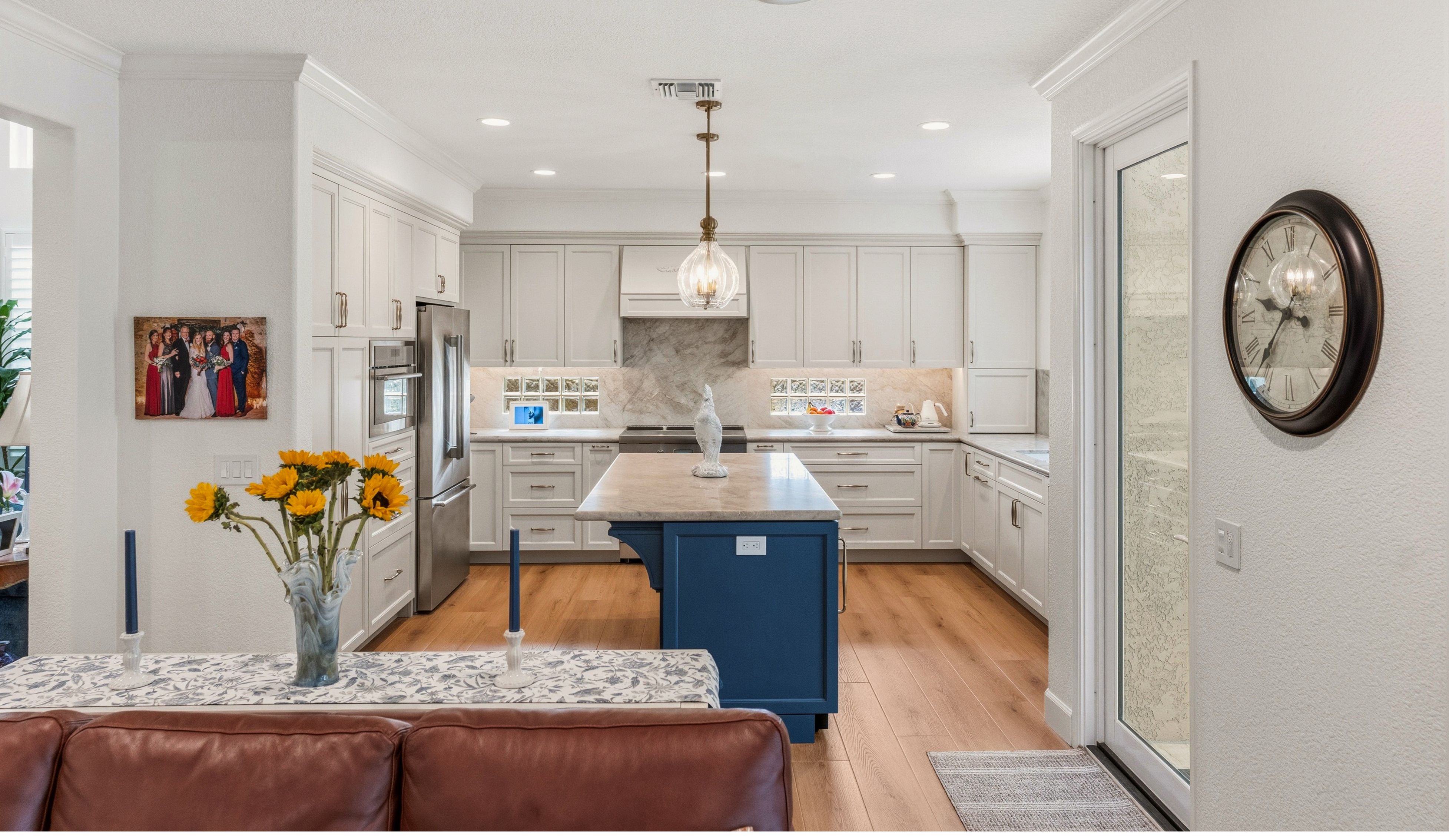 Open Carmel Valley kitchen remodel with white cabinetry, blue island, wood-look flooring and adjacent dining area.