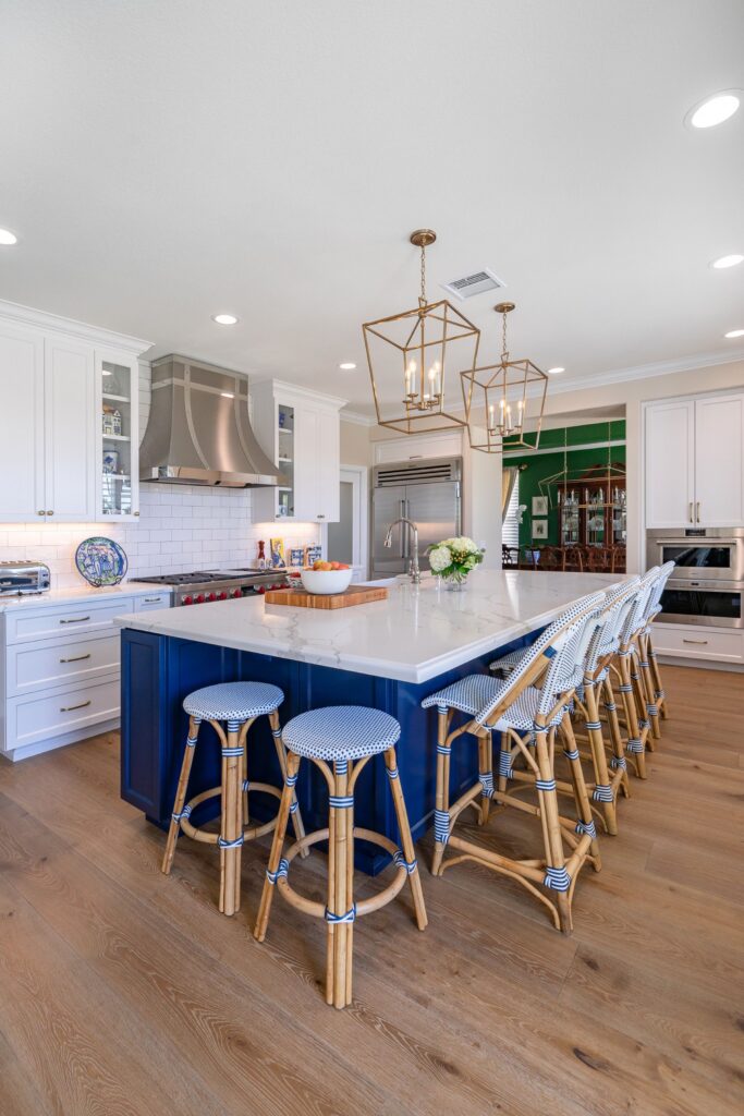 Kitchen remodel with large blue island, veined white countertops, brass lantern pendants and seating for six.