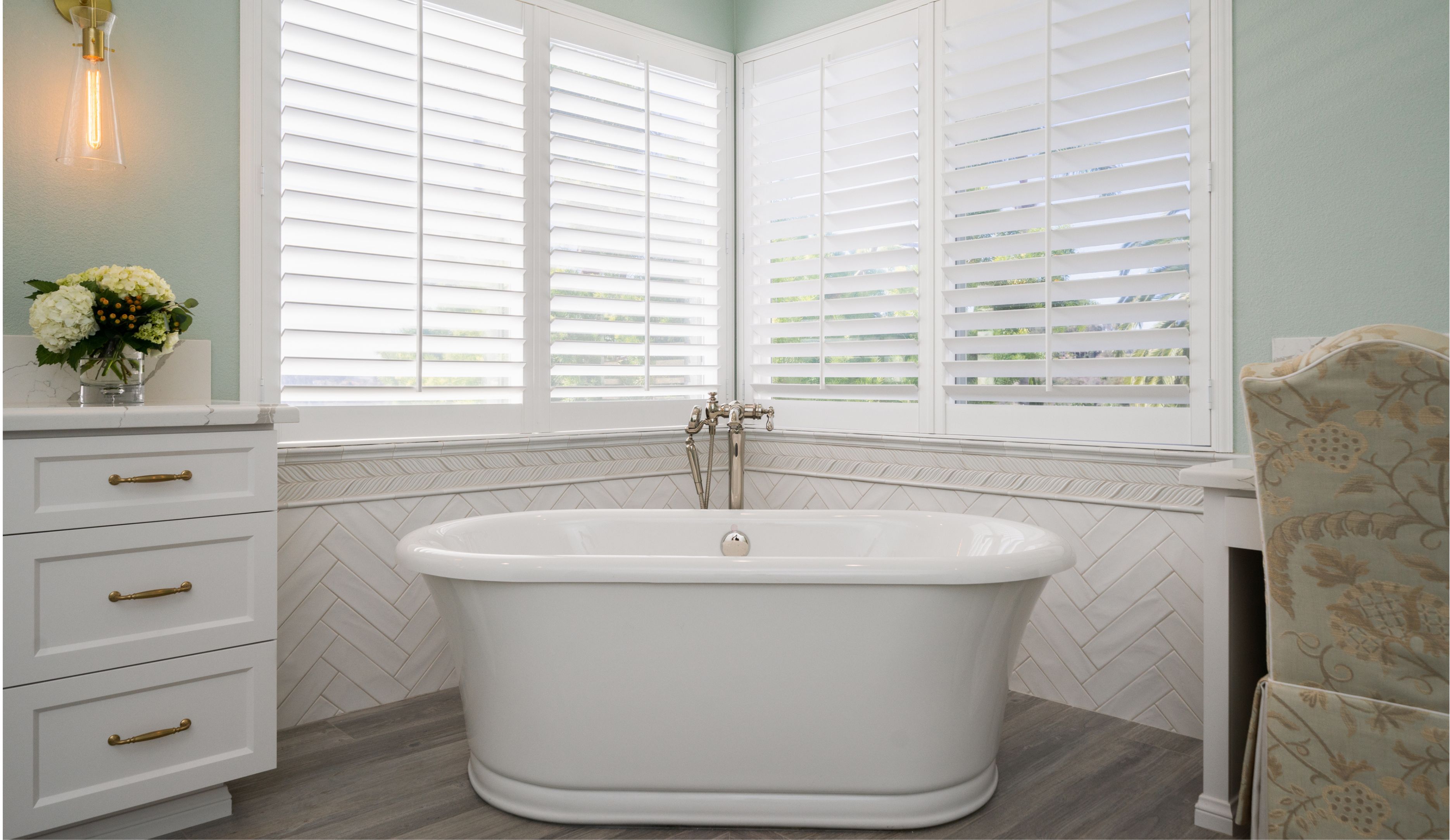 Carmel Valley primary bath remodel with freestanding tub, white herringbone tile, plantation shutters and gray flooring.