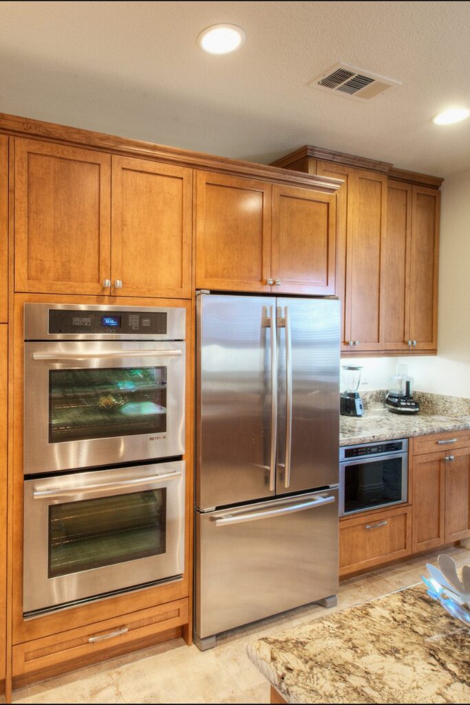 Built-in stainless double wall oven and French-door refrigerator flanked by wood cabinetry