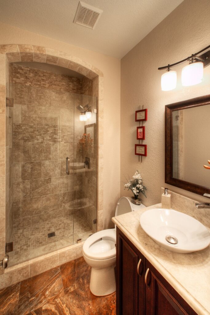 Bathroom with arched glass shower, travertine tile surround, vessel sink and dark wood vanity