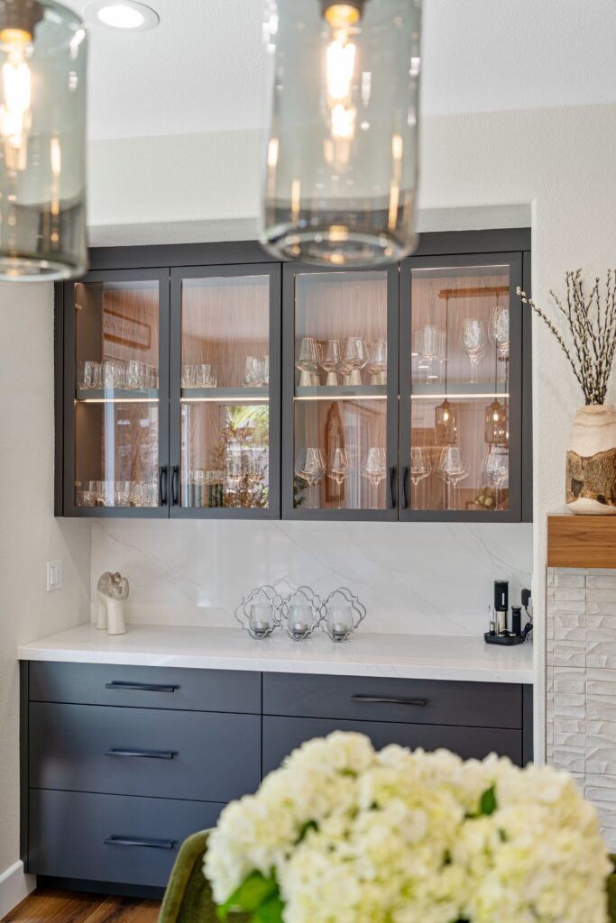 Dining room built-in with dark glass-front cabinets, base drawers, light countertop and display lighting