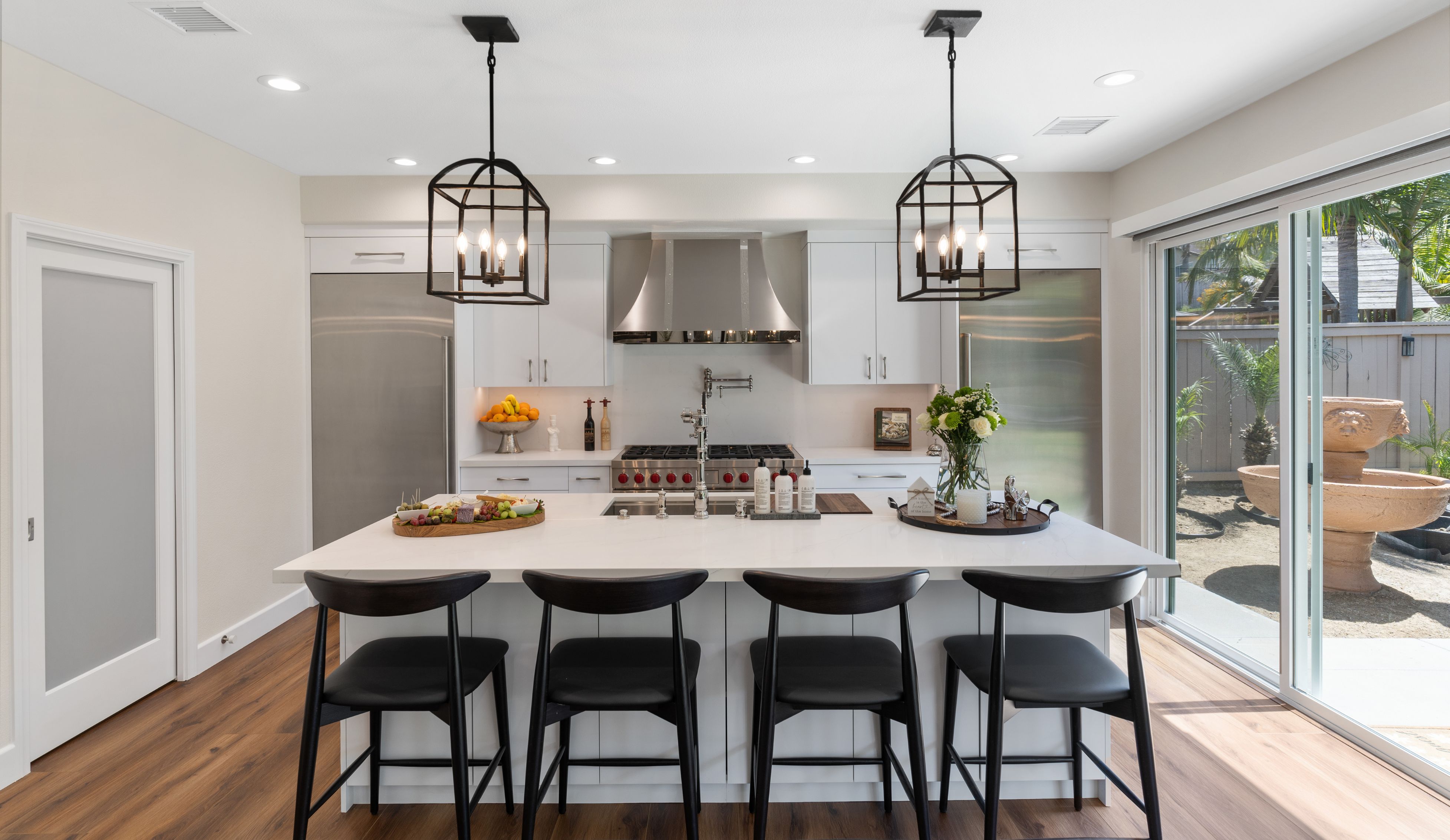 Chula Vista remodeled kitchen with oversized white island, four stools, lantern pendants and stainless appliances
