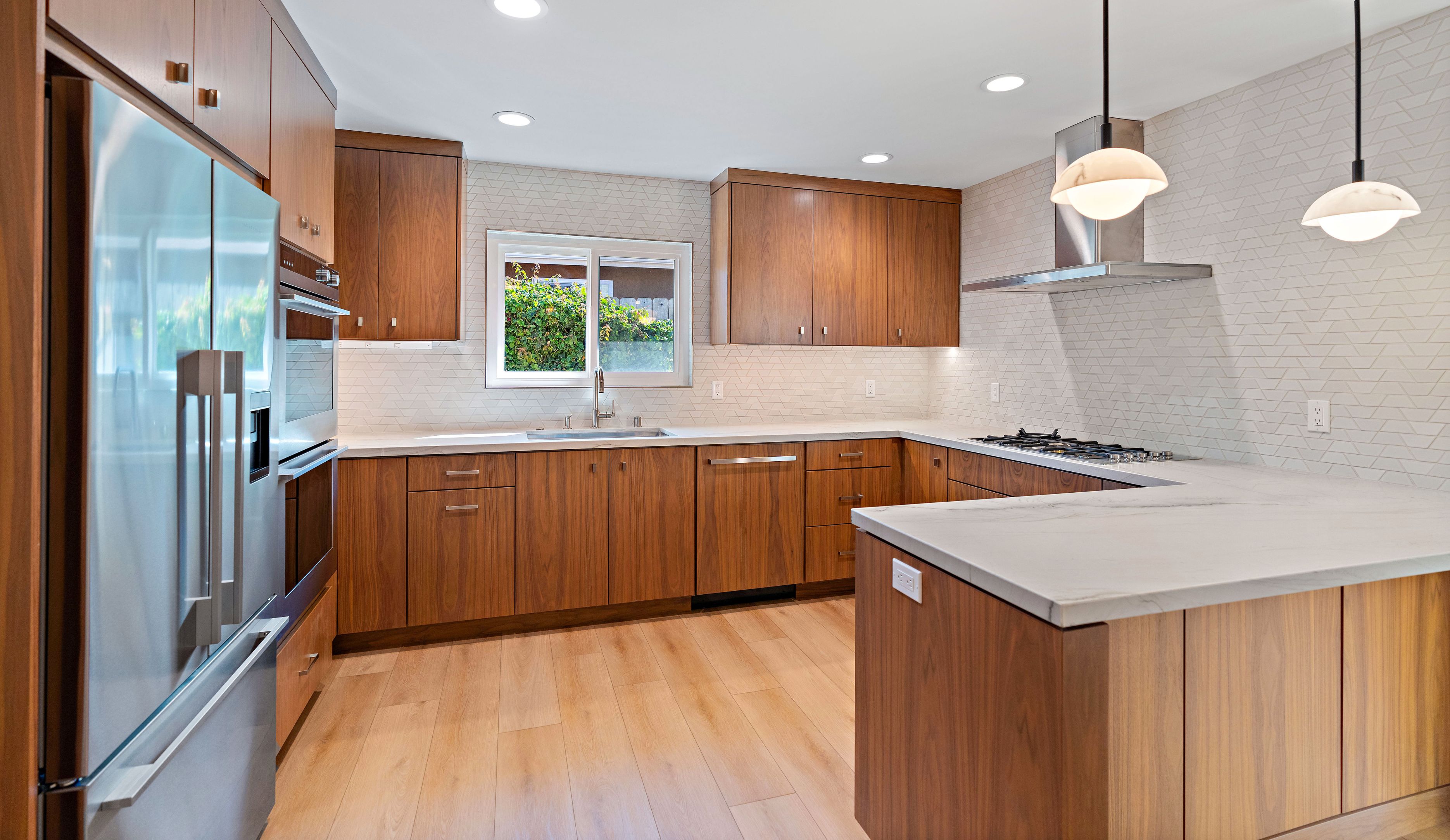 Del Mar kitchen remodel with walnut cabinetry, peninsula, white stone counters, geometric backsplash and pendant lights
