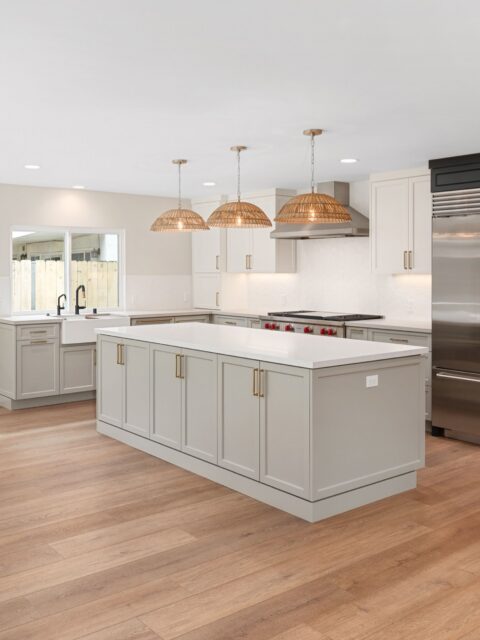 Clairemont kitchen remodel with large island, white cabinetry, farmhouse sink, woven pendants and wood-look flooring.