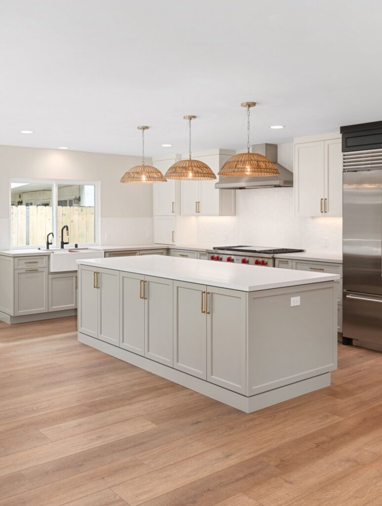 Clairemont kitchen remodel with large island, white cabinetry, farmhouse sink, woven pendants and wood-look flooring.
