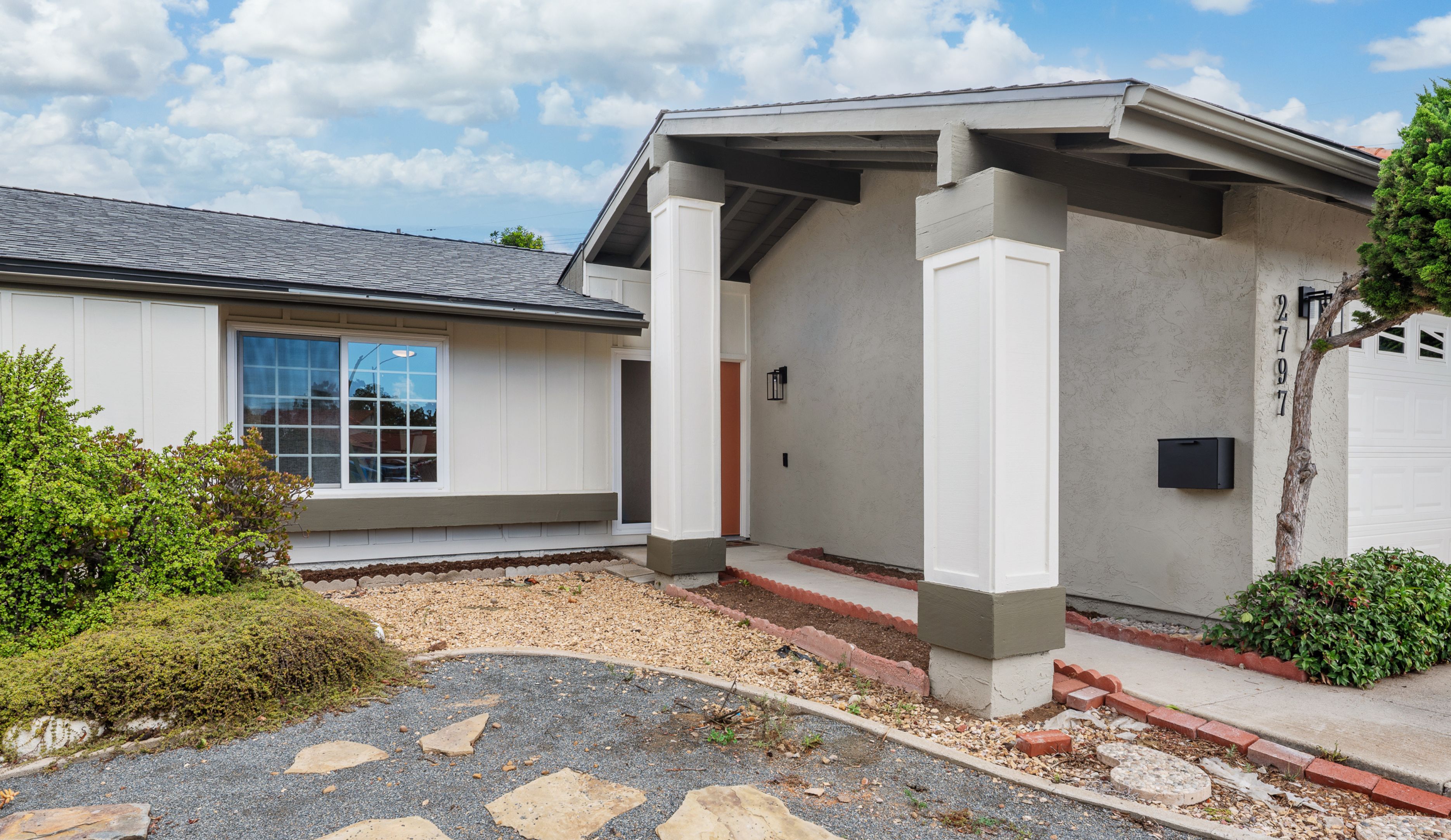 Clairemont whole-home remodel exterior with covered entry, stucco and panel siding, updated columns and front landscaping.