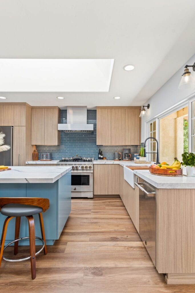 Kitchen remodel with light wood cabinets, blue tile backsplash, skylight, farmhouse sink and blue island