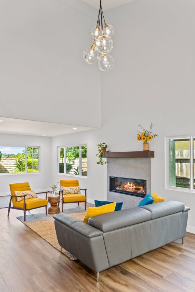 Remodeled family room with vaulted ceiling, linear fireplace, gray sofa and yellow accent chairs