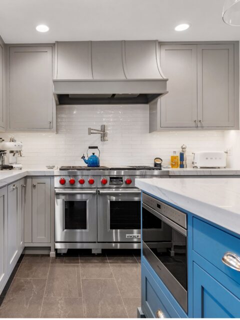 Del Mar kitchen remodel with gray inset cabinetry, blue island, white counters, stainless appliances and glass pendants.