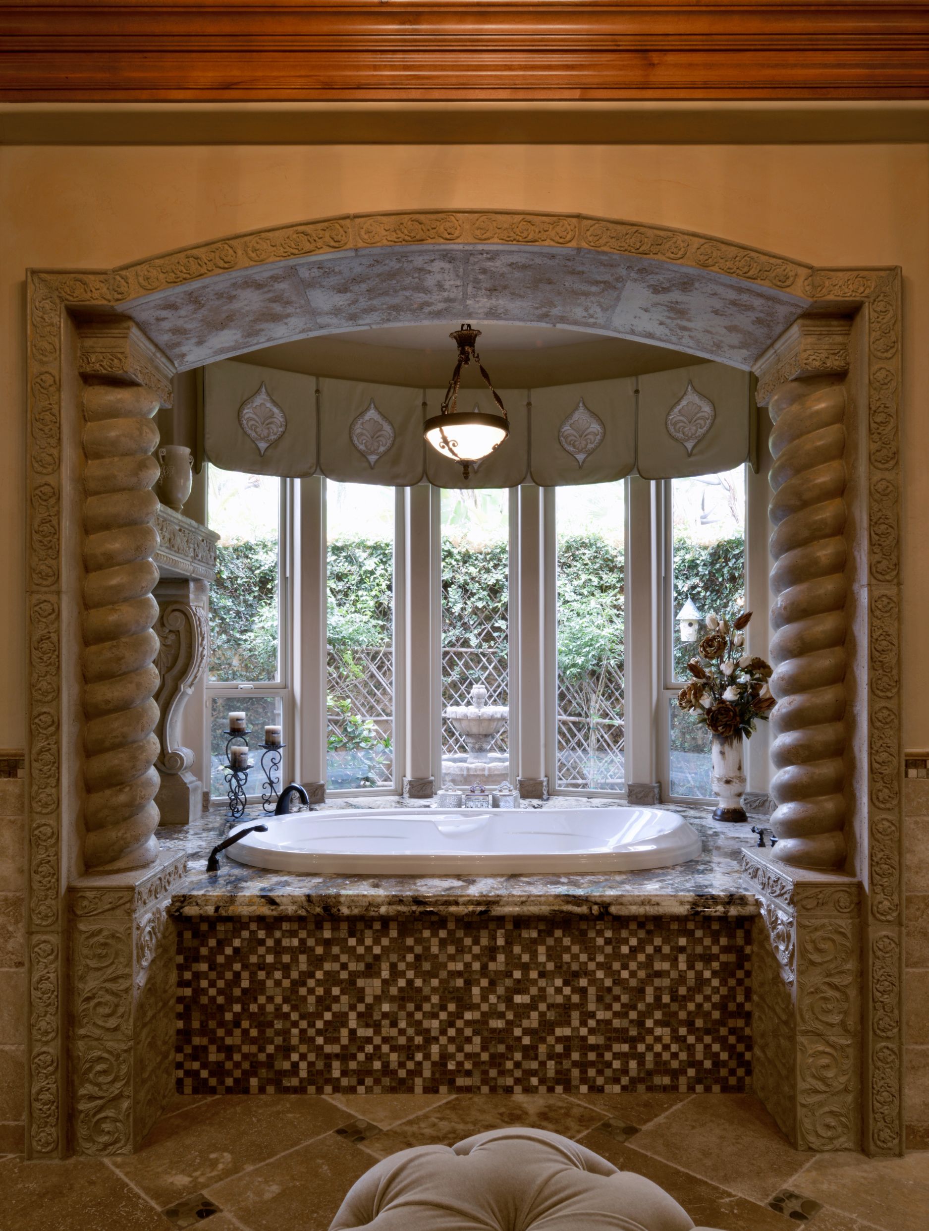 El Cajon bathroom remodel with soaking tub, granite surround, mosaic tile, carved stone arch and spiral columns.