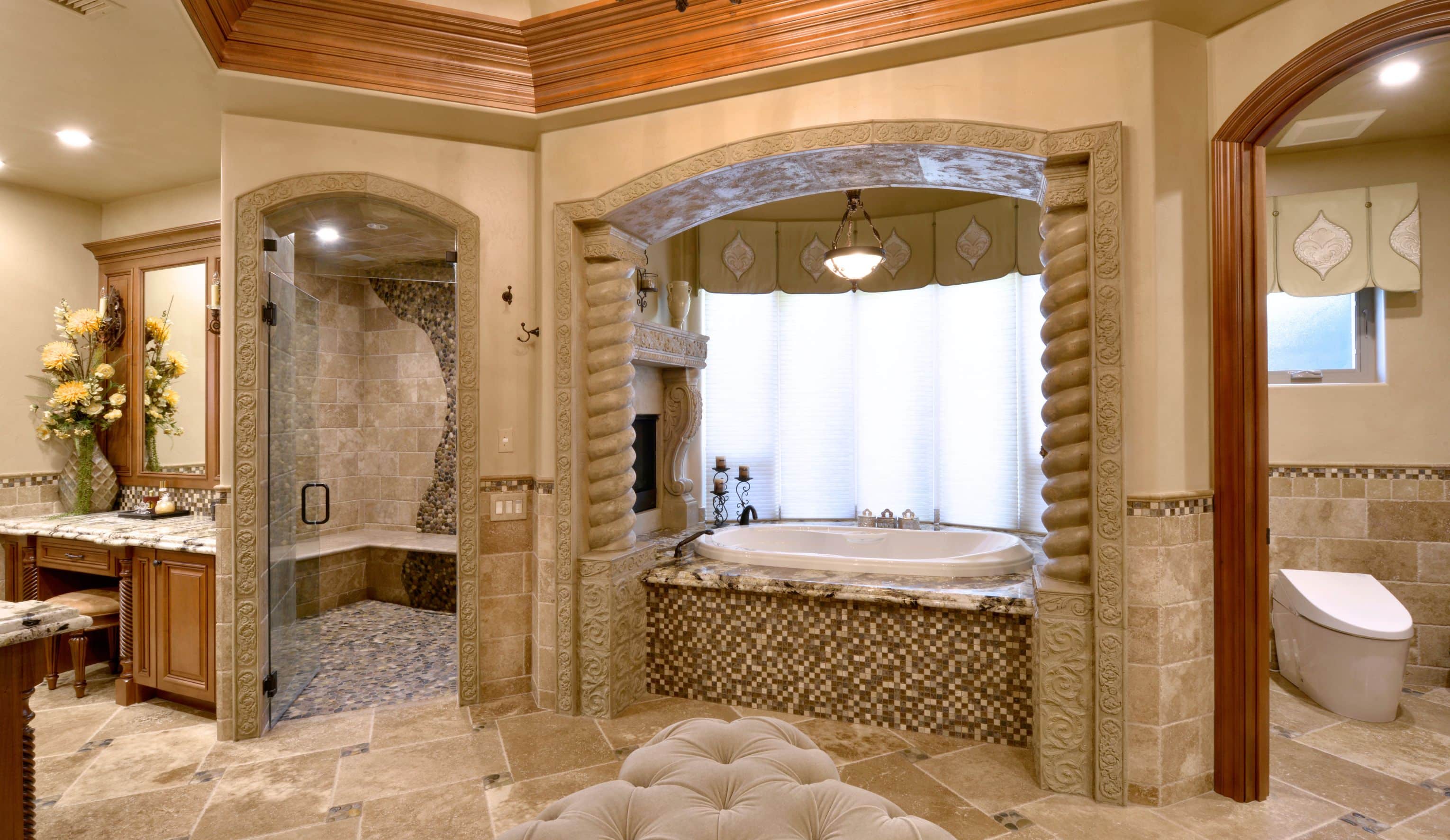El Cajon primary bathroom remodel with glass shower, arched tub alcove, stone tile, wood vanity and separate toilet room.