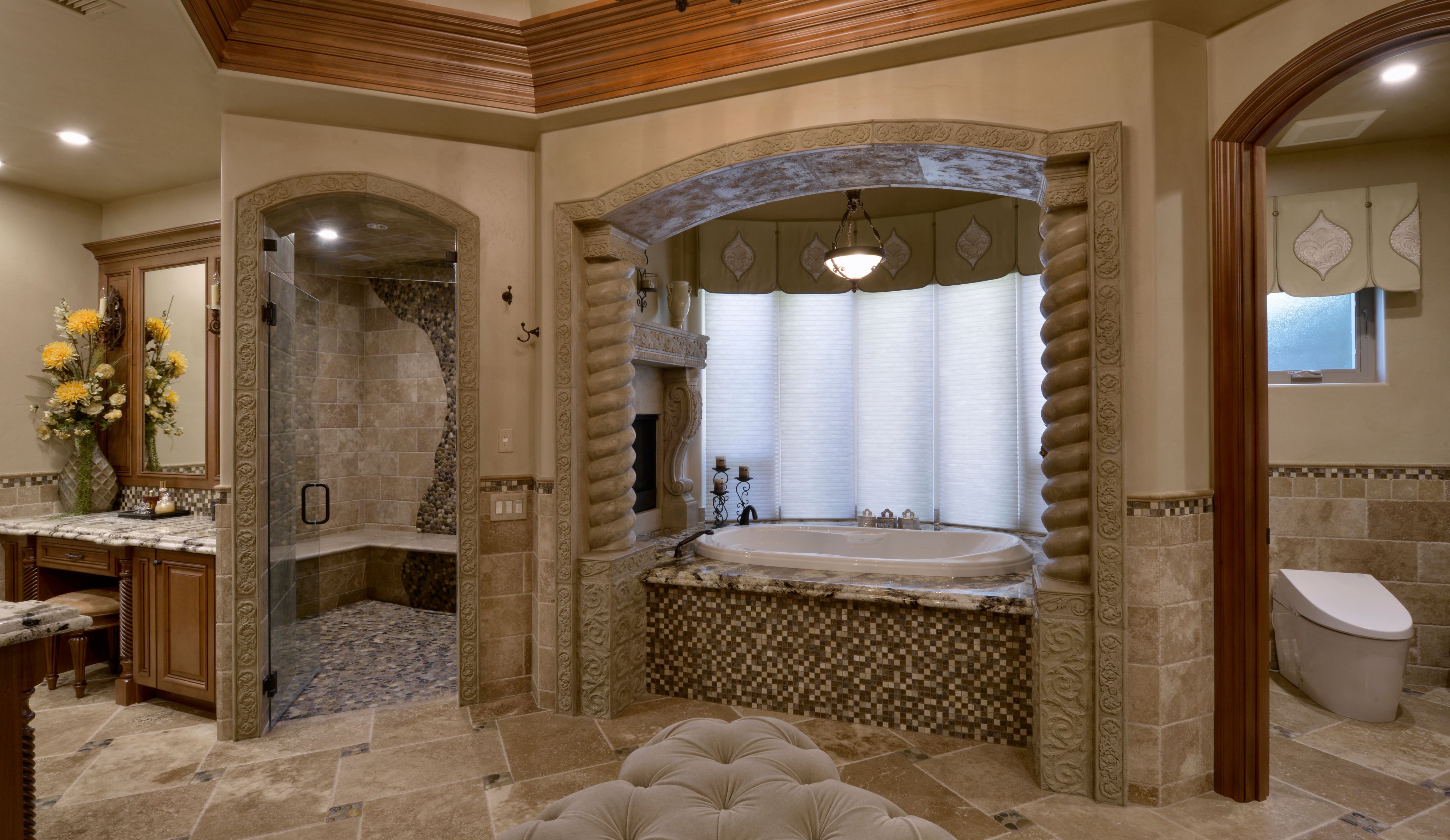 El Cajon primary bathroom remodel with glass shower, arched tub alcove, stone tile, wood vanity and separate toilet room.