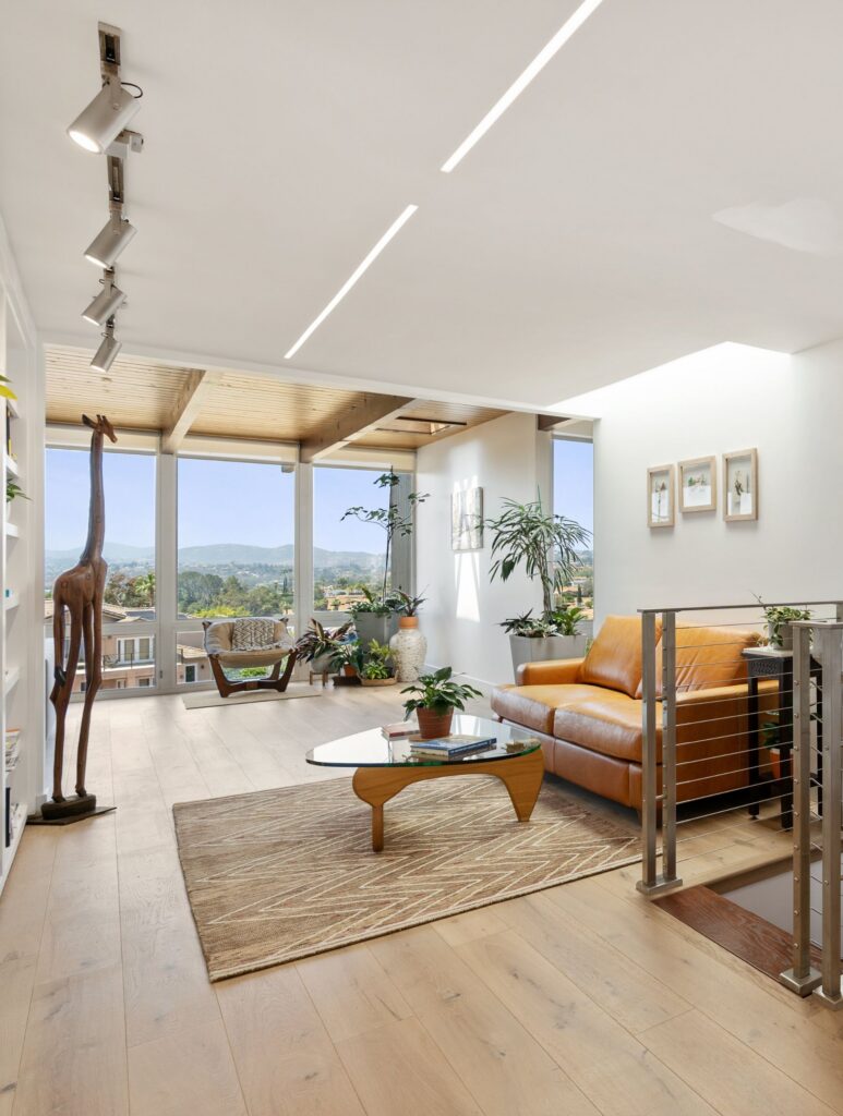 Escondido whole-home remodel with light wood floors, cable railing, exposed wood ceiling and floor-to-ceiling windows.