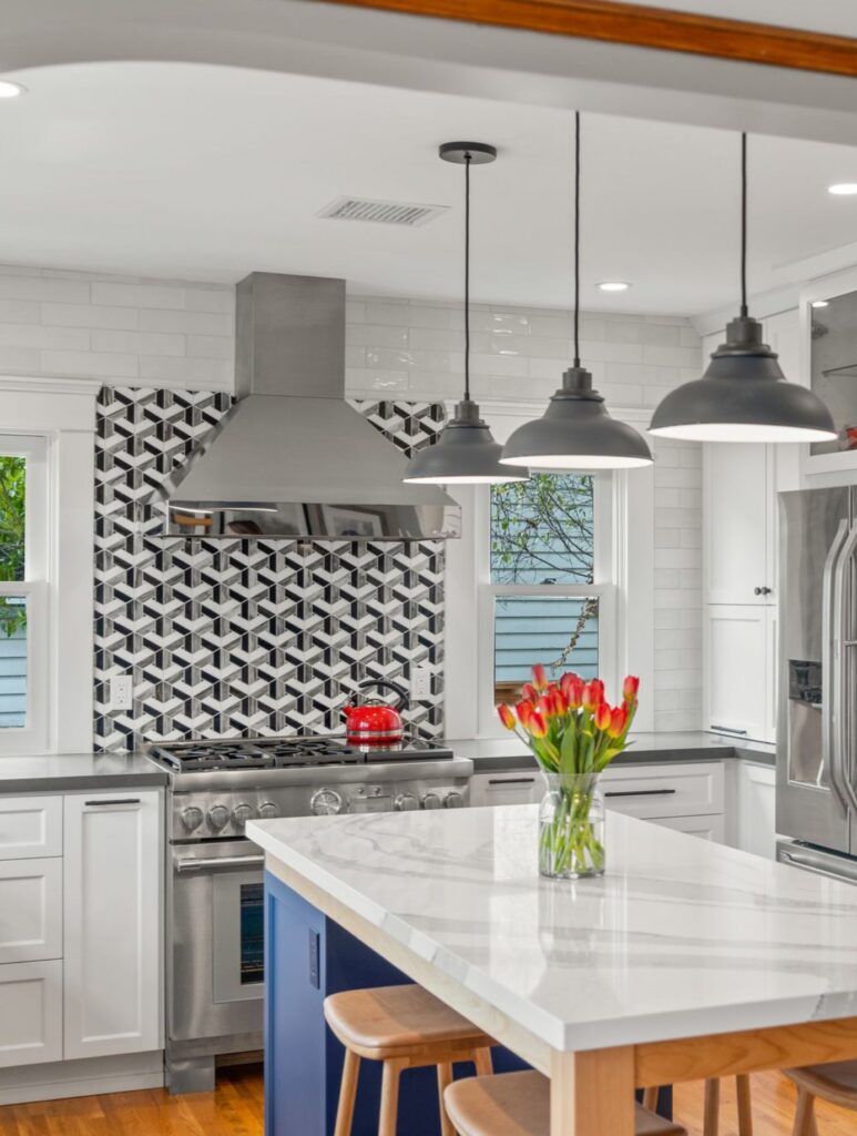 Hillcrest kitchen remodel with blue seating island, white cabinetry, geometric backsplash, stainless range and pendant lights.