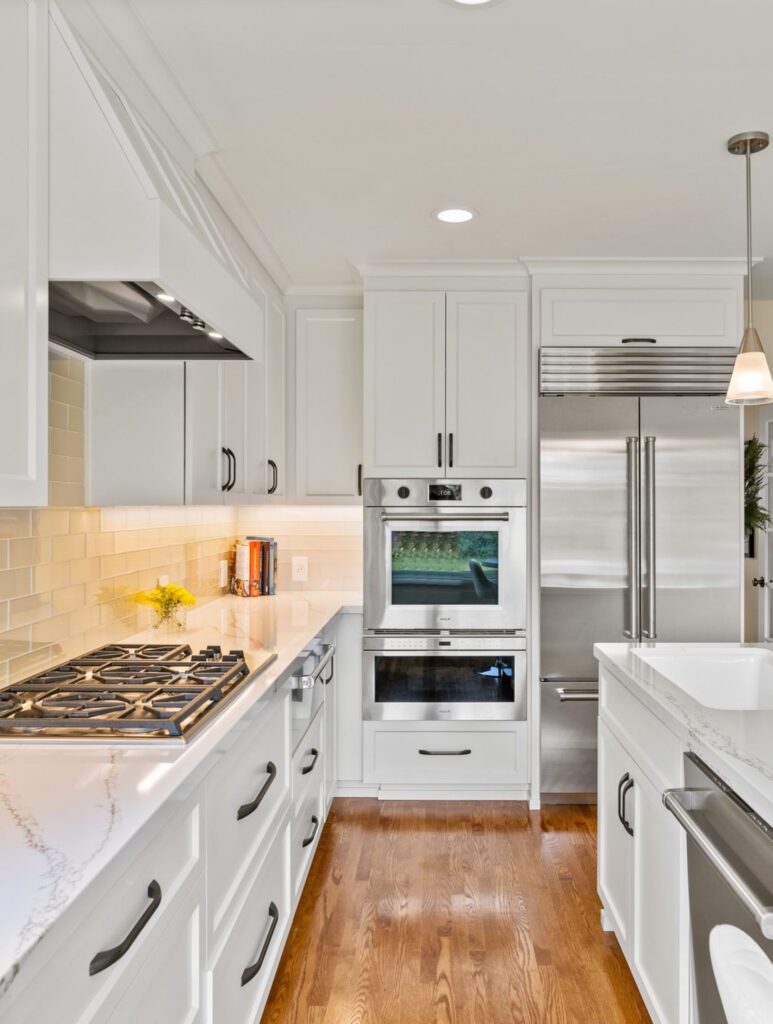 La Mesa kitchen remodel with white cabinetry, veined countertops, stainless appliances, wood floors and island seating.
