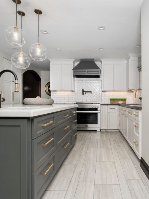 Normal Heights kitchen remodel with gray island, white cabinetry, brass hardware, glass pendants and herringbone backsplash