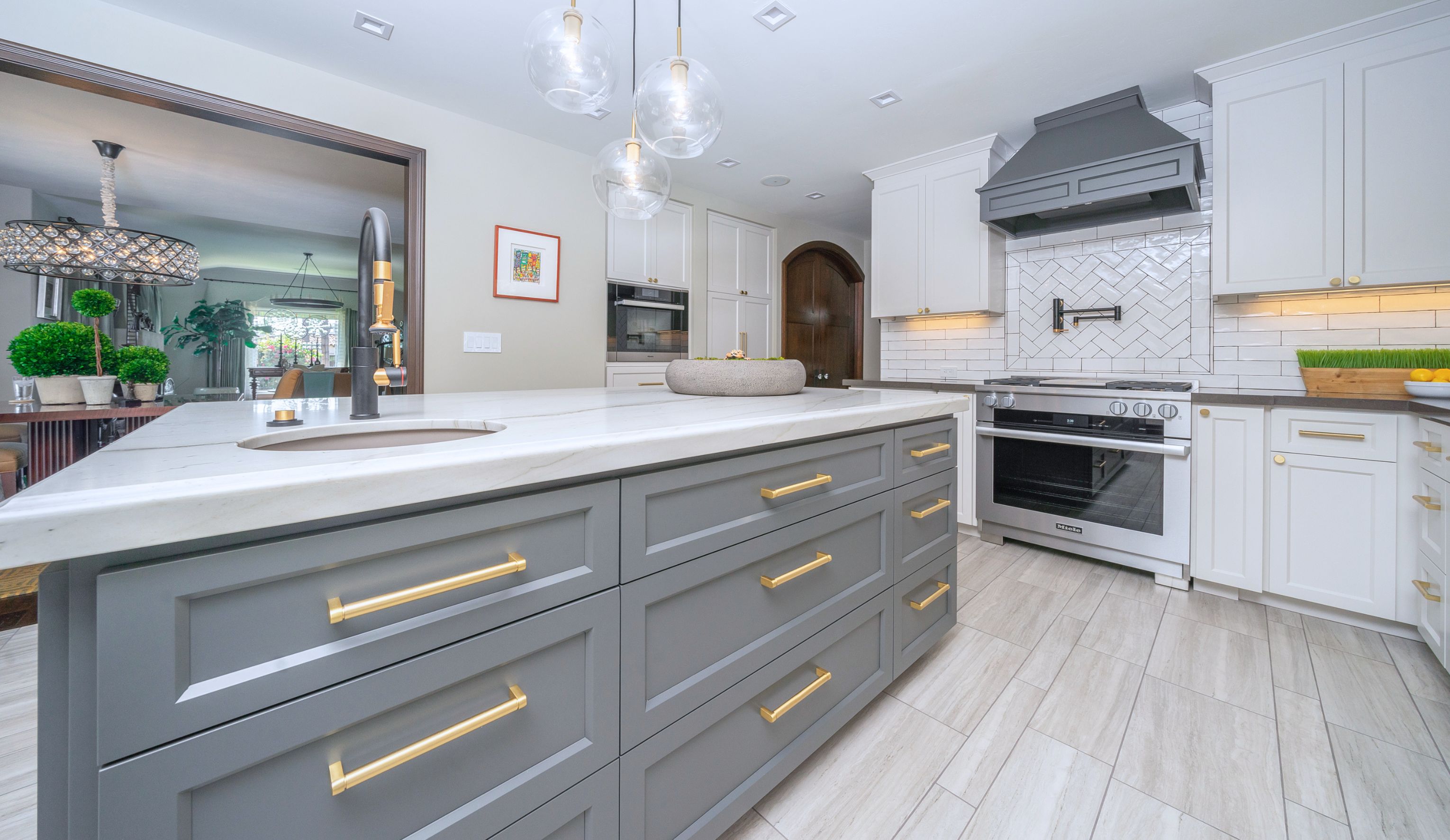 Open-concept kitchen and living area with black waterfall island, dark cabinetry, fireplace and light wood flooring