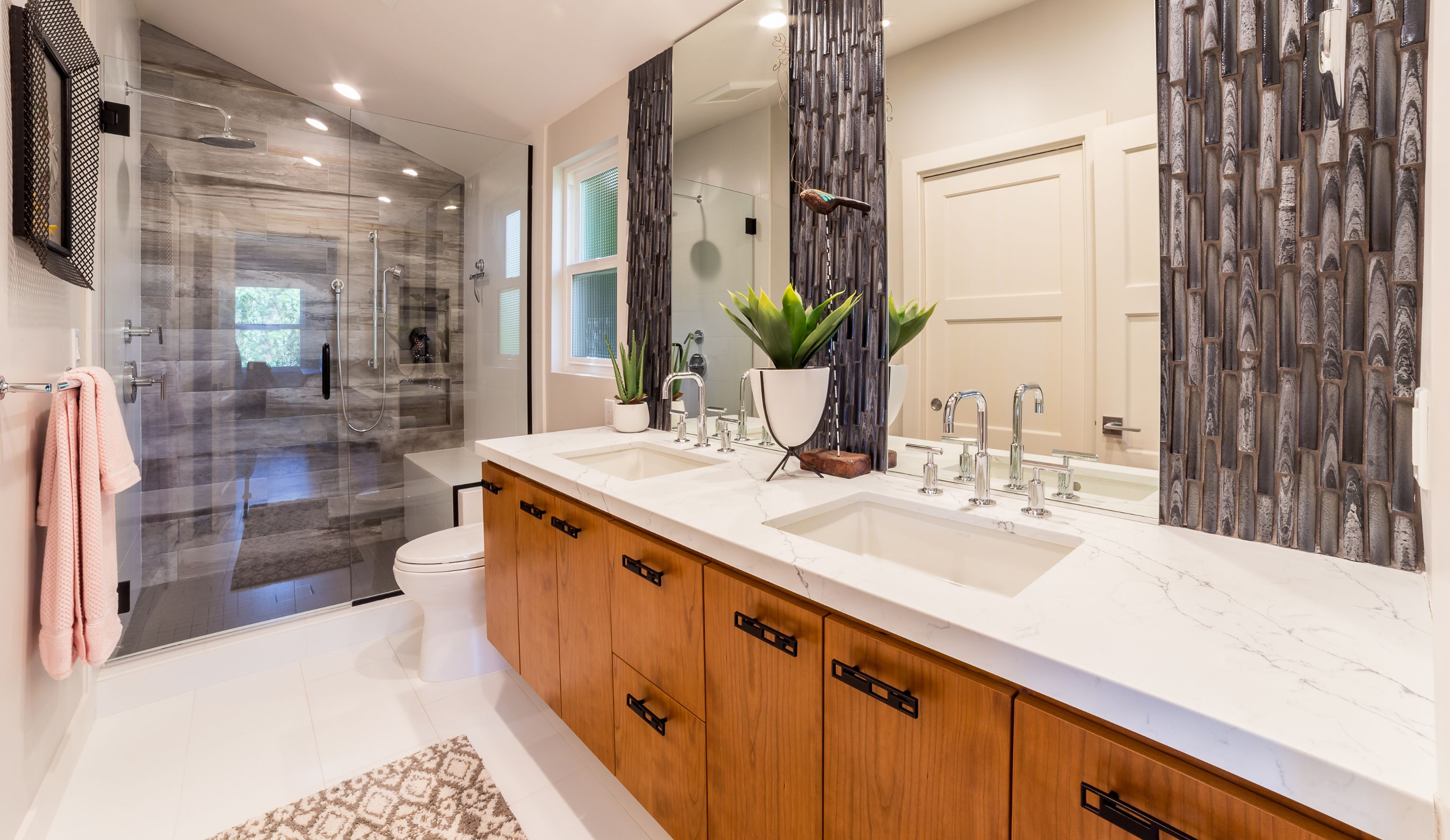 Laundry room with stacked washer and dryer, dark cabinetry, white counter and black-and-white patterned tile floor