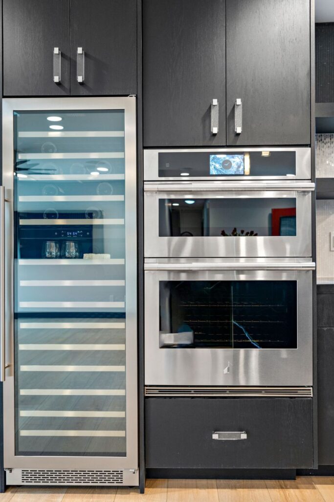 Kitchen appliance wall with glass-front wine cooler, stacked stainless ovens and black cabinetry