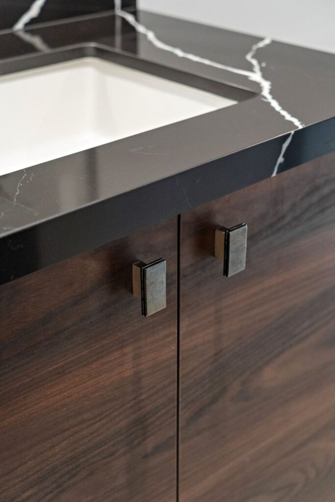 Dark wood bathroom vanity with black veined countertop, undermount sink and rectangular cabinet pulls