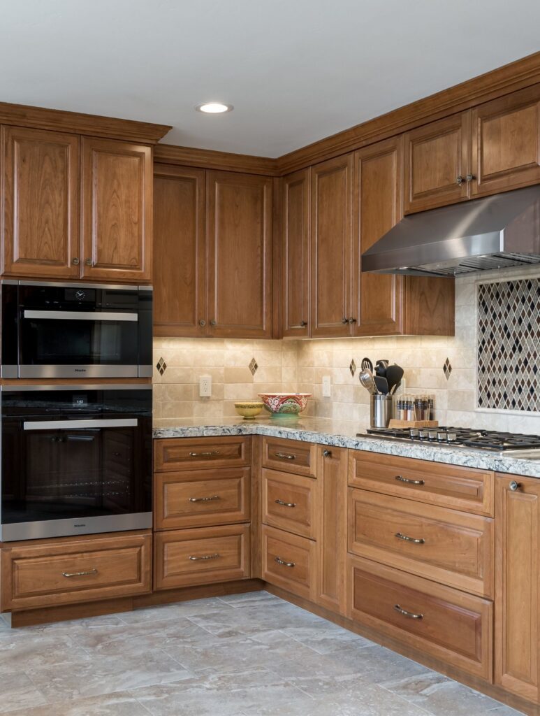 Ocean Beach whole-home remodel kitchen with raised-panel wood cabinetry, double wall ovens, stone counters and tiled backsplash.