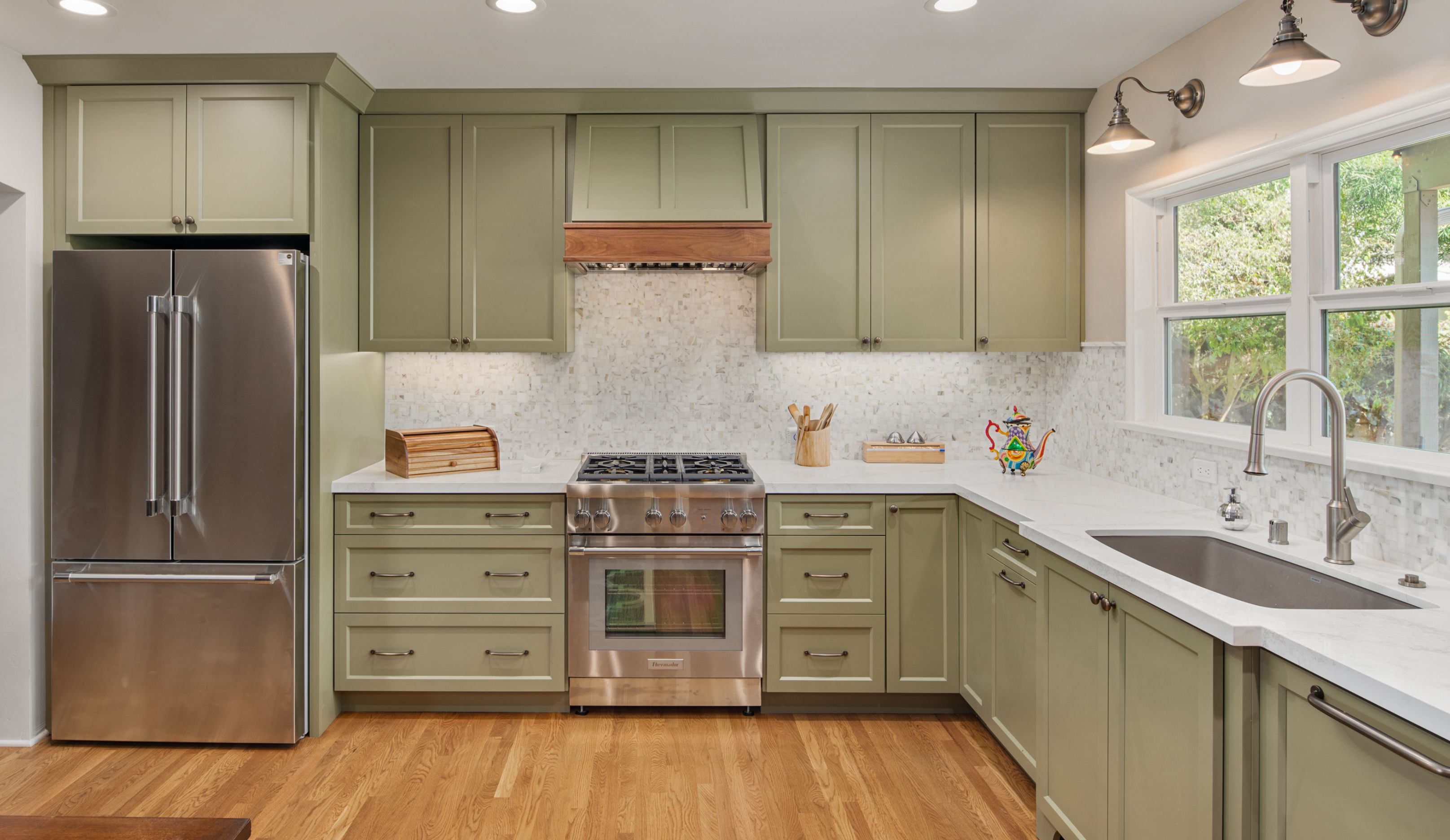 Ocean Beach kitchen remodel with sage cabinetry, stainless appliances, windowed sink wall and light mosaic backsplash.