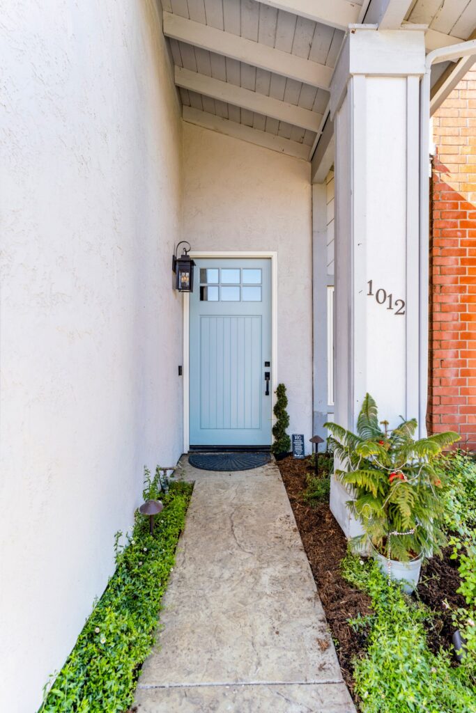 Front entry with light blue craftsman-style door, glass panel lantern and concrete walkway