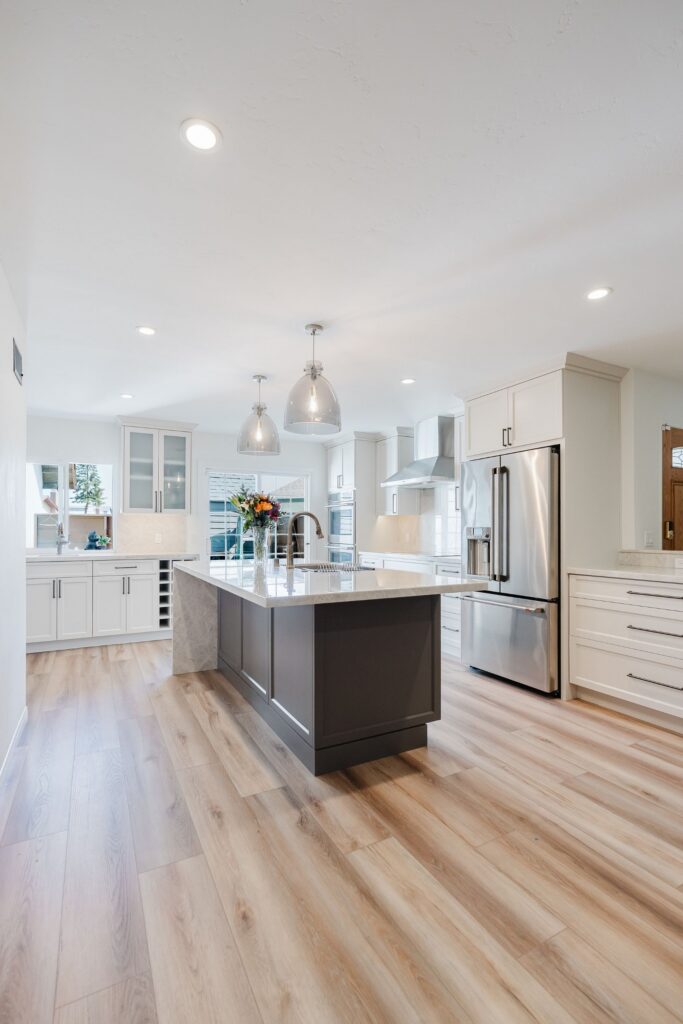 Mira Mesa kitchen remodel with dark island, white shaker cabinetry, stainless appliances and light wood-look flooring.