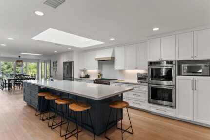 Open-concept Poway kitchen with navy island, white cabinetry, quartz counters and skylights