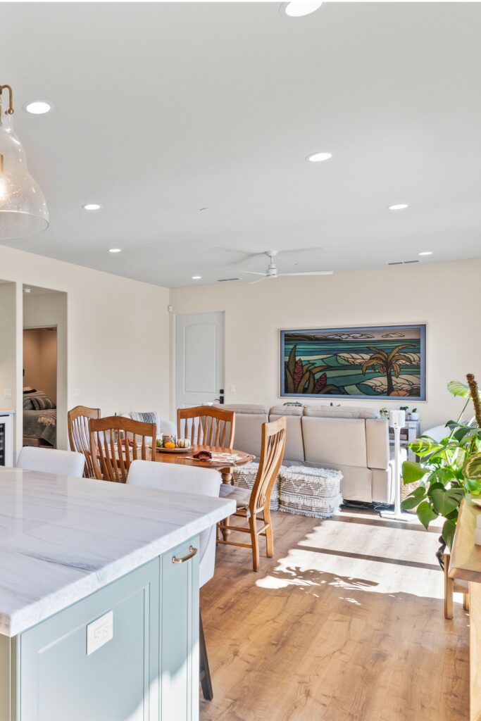 Open-plan ADU living and dining area with wood-look flooring, recessed lighting and kitchen island.