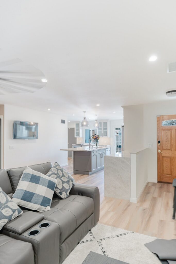 Living room opening to remodeled kitchen with dark island, pendant lights, recessed lighting and wood-look flooring.
