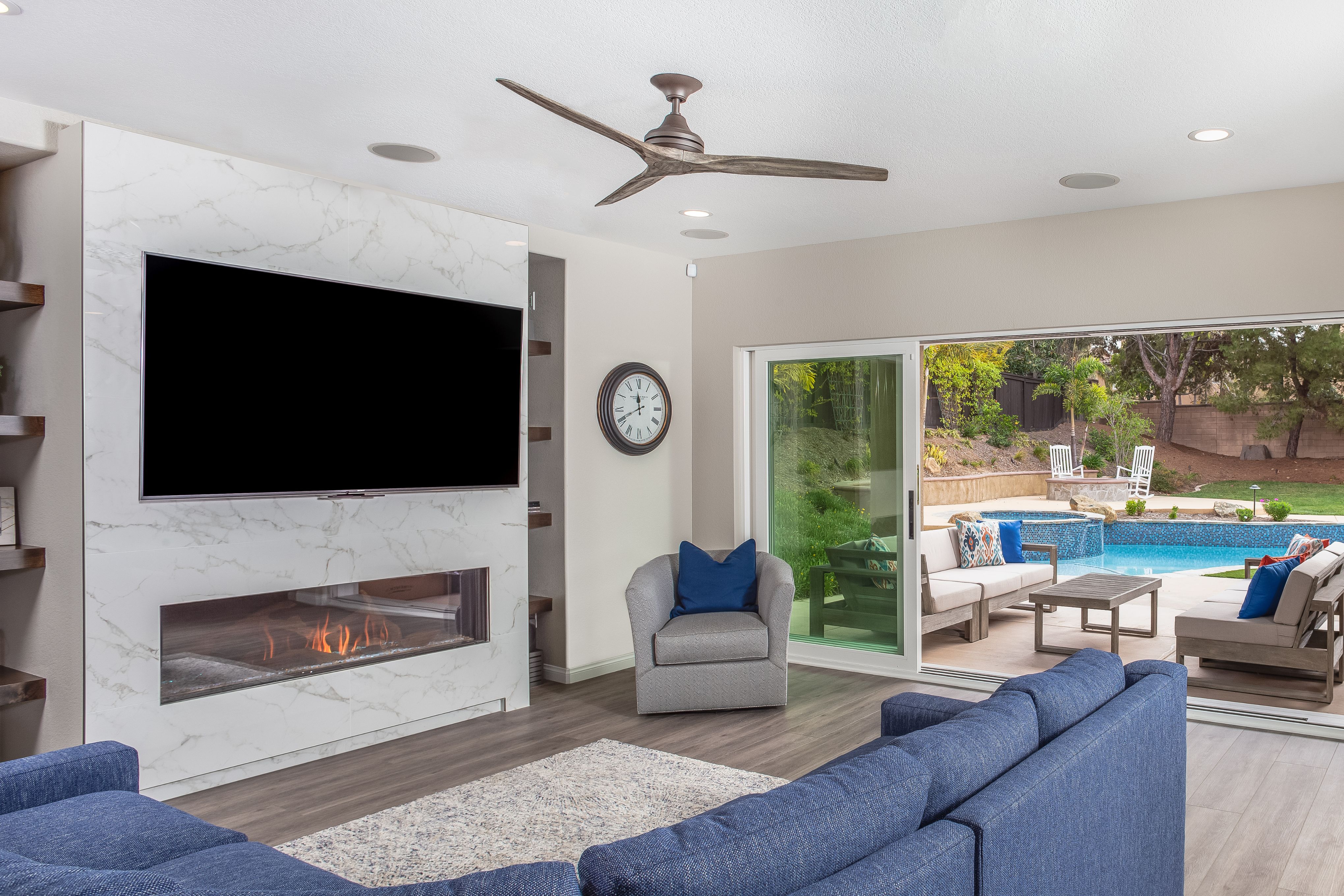 Family room with marble-look fireplace wall, mounted TV and sliding doors to pool patio