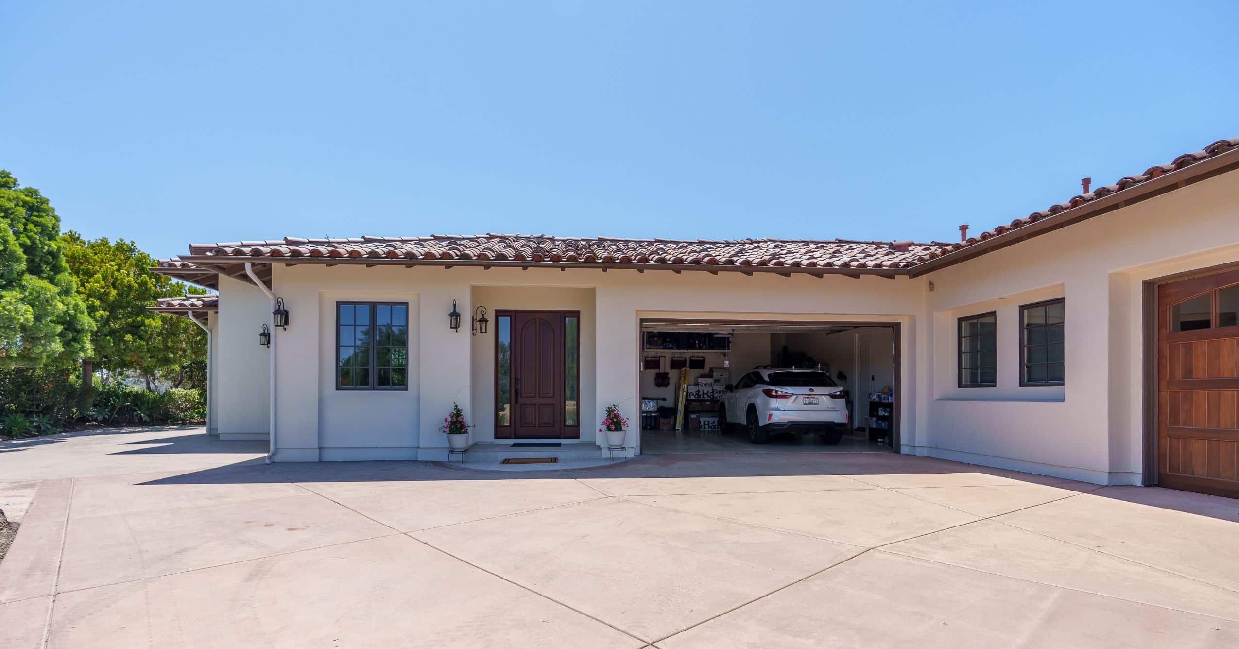 Exterior view of the attached ADU with white stucco, wood entry door, garage opening, and tiled roof.