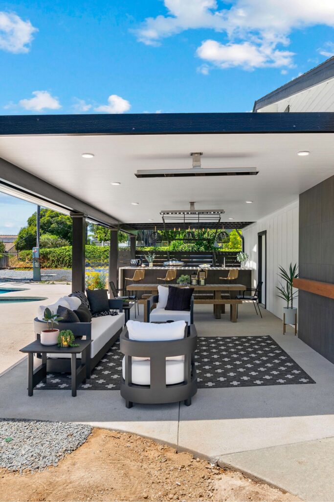 Covered patio with lounge seating, wood dining table, outdoor kitchen, ceiling heaters and recessed lights