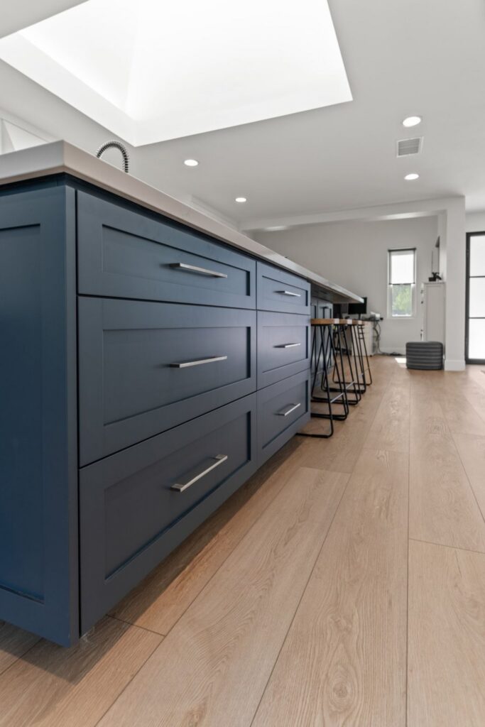 Navy kitchen island with deep storage drawers, quartz countertop, skylight and wood-look flooring