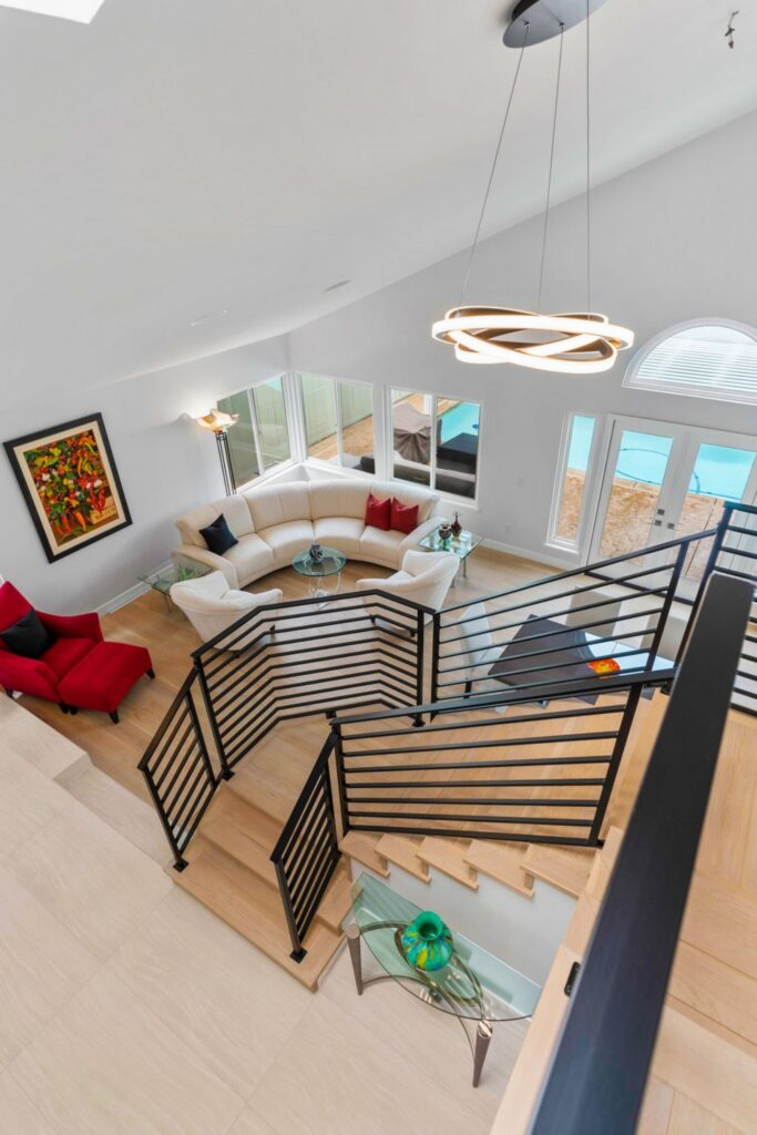 Upper-level view of open staircase with black railings, light wood treads and living room below.