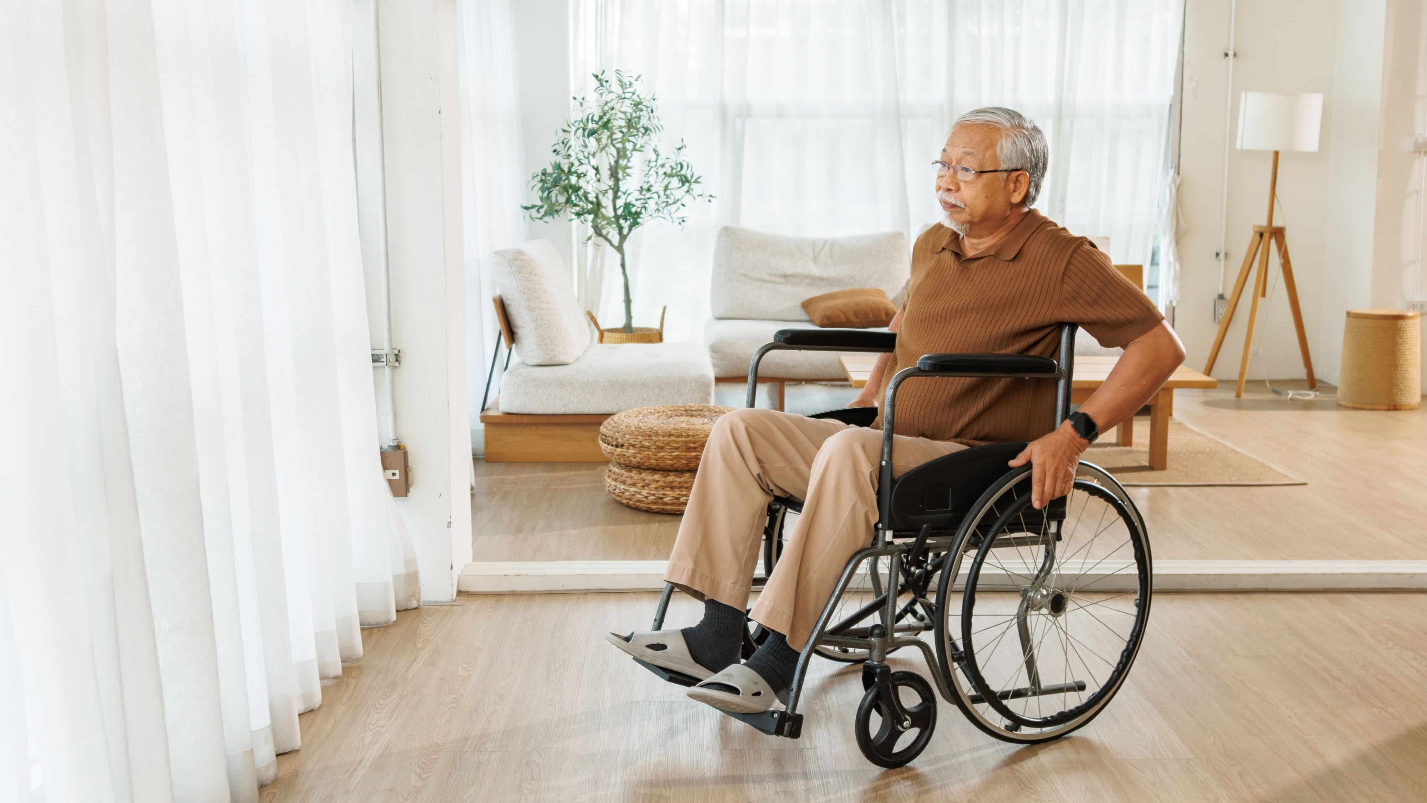 Older adult using a wheelchair in a bright, open living room with wide pathways and level flooring.