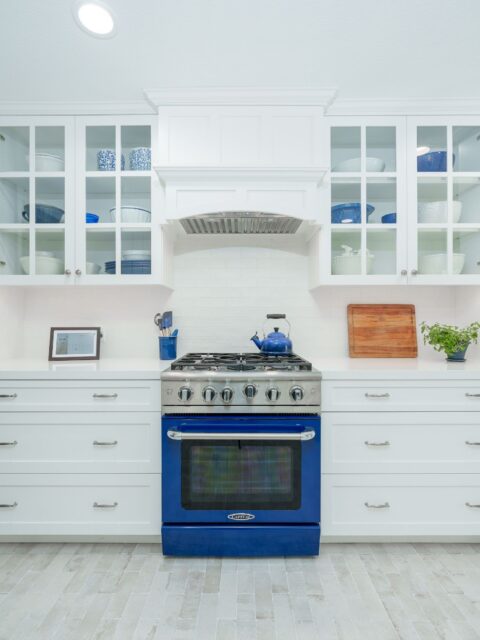 San Diego kitchen remodel with blue range, white shaker and glass-front cabinets, custom vent hood and quartz counters