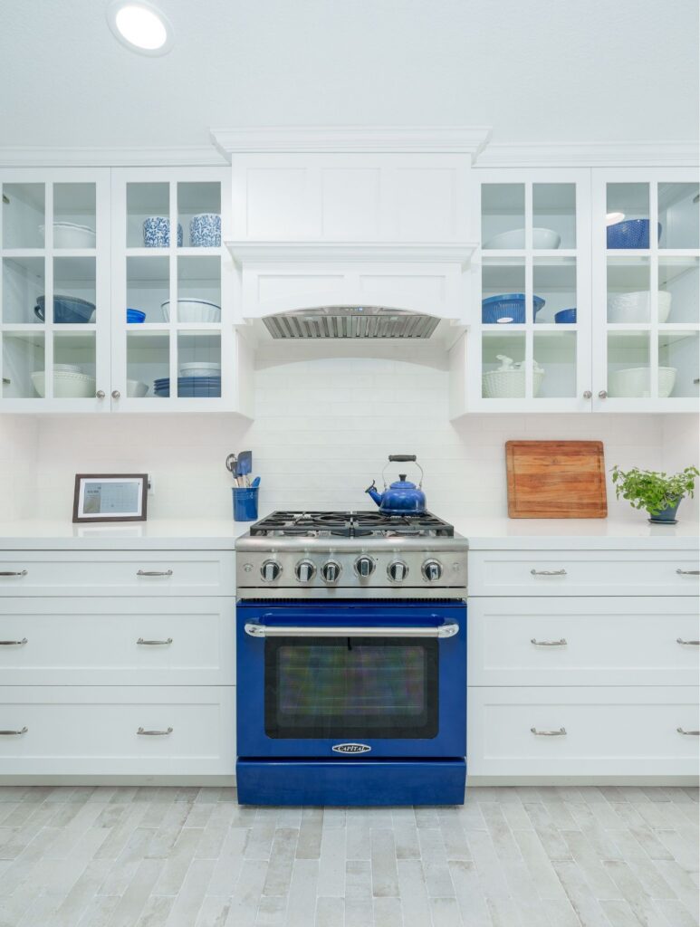 San Diego kitchen remodel with blue range, white shaker and glass-front cabinets, custom vent hood and quartz counters