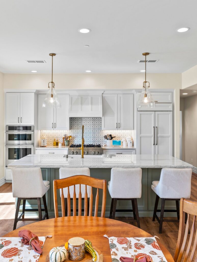 Poway ADU kitchen and dining area with large island, white cabinetry, patterned tile backsplash and pendant lighting.