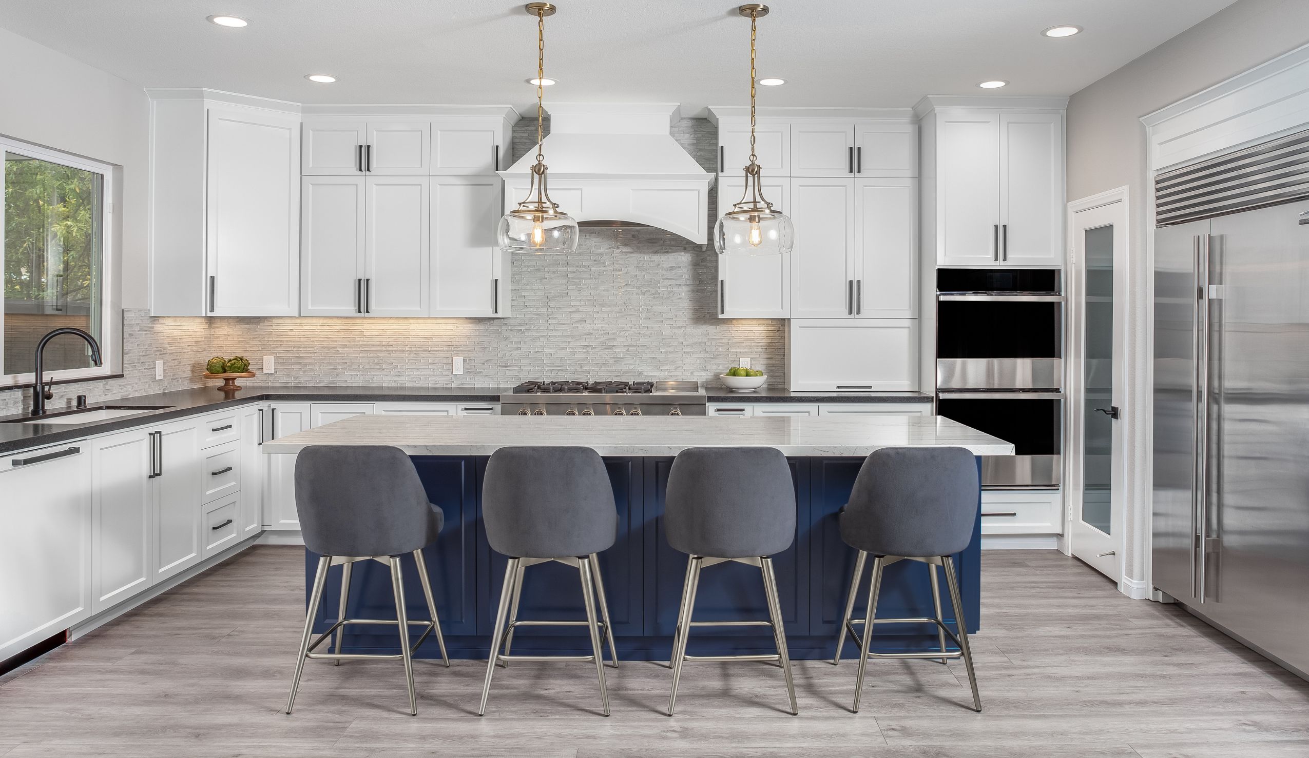 Kitchen island with quartz countertop, navy cabinetry and stainless double ovens in Rancho Peñasquitos remodel