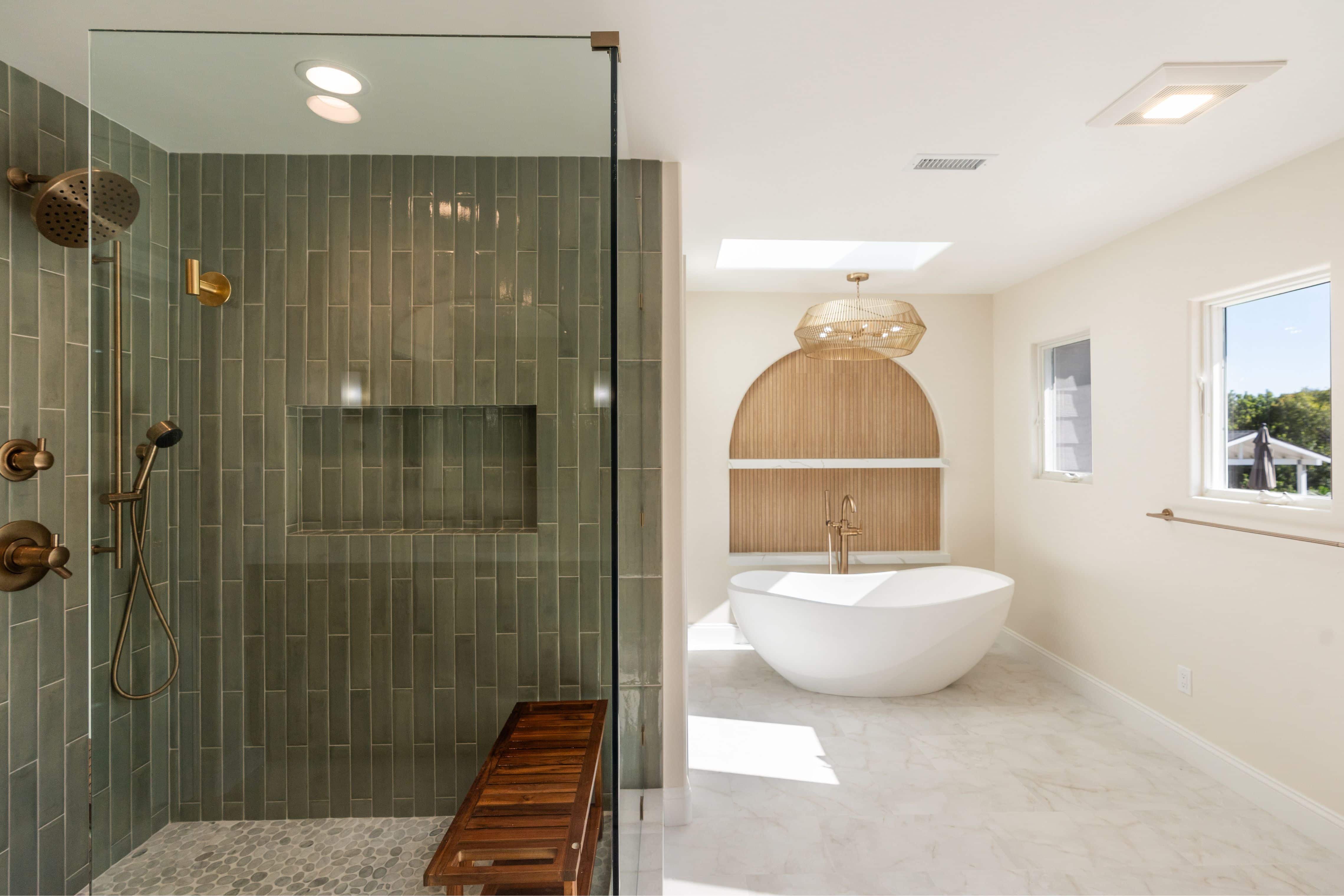 Primary bathroom with green vertical-tile shower, rain and handheld heads, pebble floor and freestanding tub beyond