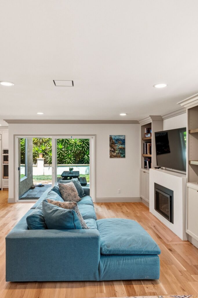 Family room with a fireplace, mounted TV and built-in shelving, wood floors and a sliding door to the patio
