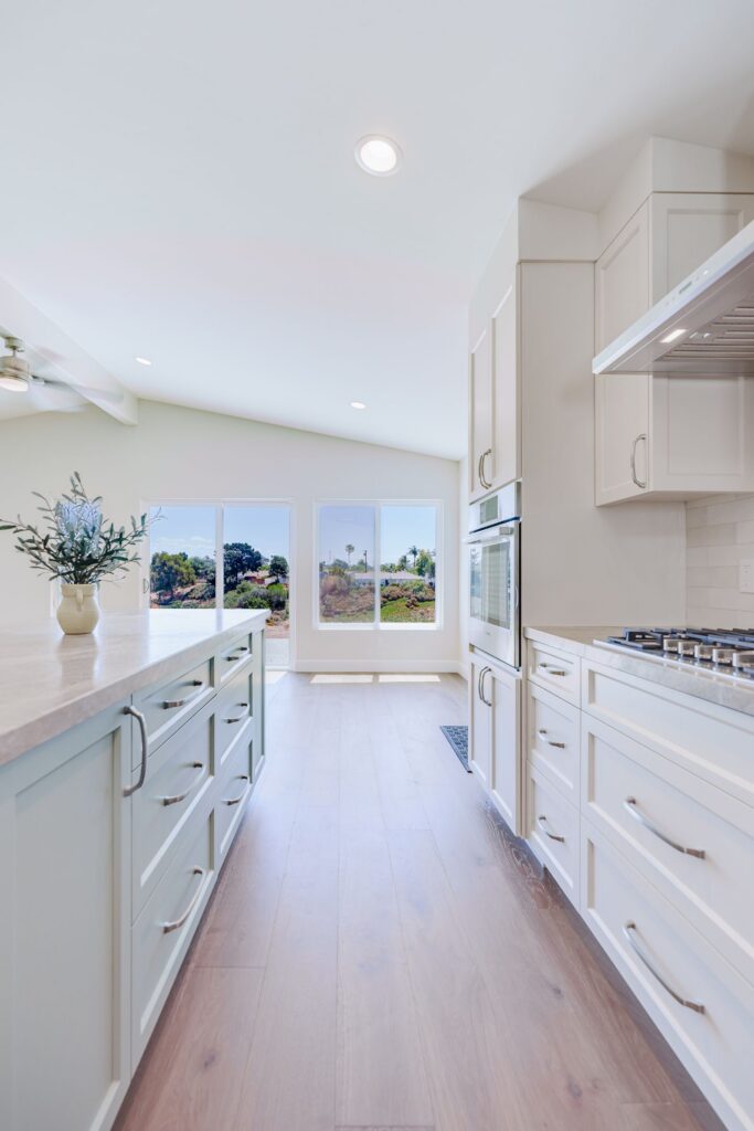 Kitchen walkway between the island drawers and a white cabinet wall with a wall oven and gas cooktop