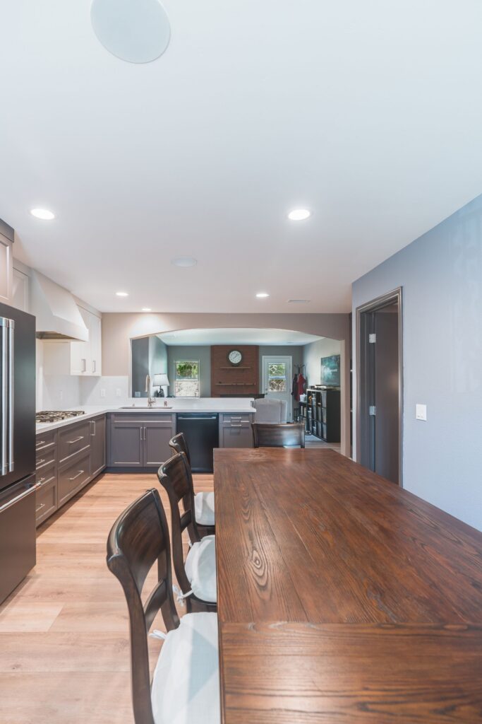 L-shaped San Diego kitchen with gas cooktop, white hood, black dishwasher and arched opening to the family room