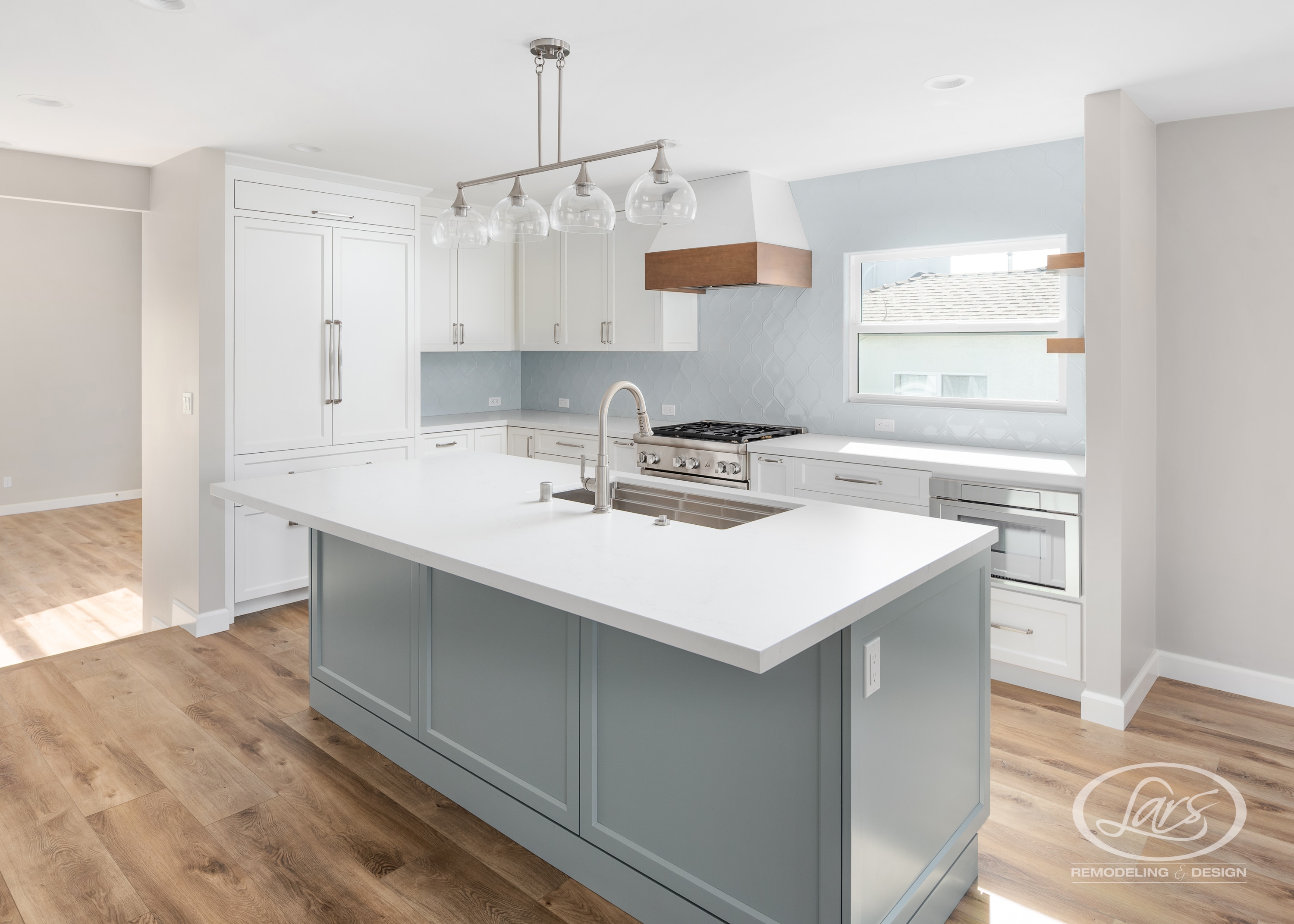 Modern San Diego kitchen remodel by Lars Remodeling & Design featuring a large blue-gray island, white cabinetry, and stainless steel appliances.